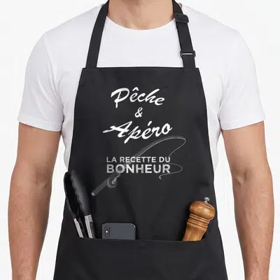 Tablier de cuisine noir avec une illustration de canne à pêche et le texte blanc Pêche et Apéro la recette du bonheur.