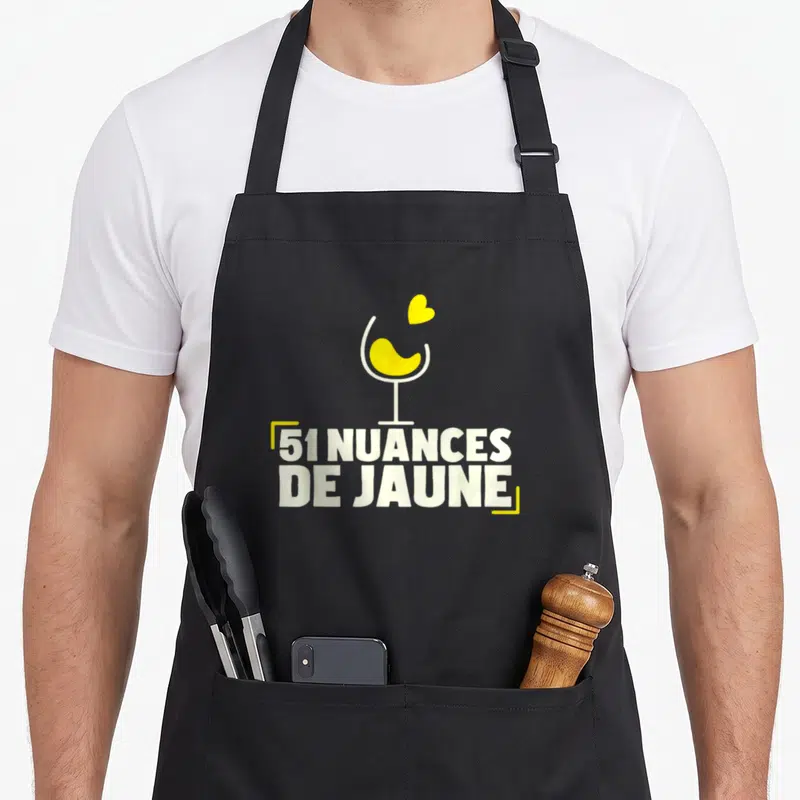 Tablier de cuisine noir avec illustration verre jaune cœur et texte 51 nuances de jaune en typographie blanche.