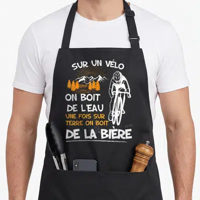 Tablier de cuisine noir avec illustration cycliste et texte Sur un vélo on boit de la bière en blanc et orange.