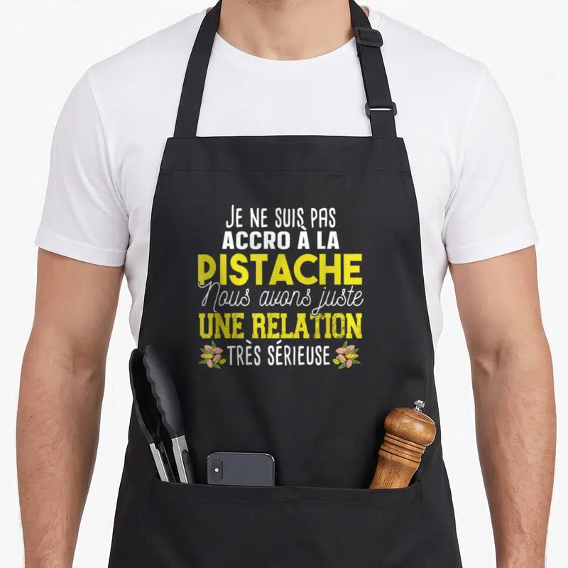 Tablier de cuisine noir avec le texte Je ne suis pas accro à la pistache et des illustrations d'amandes vertes.