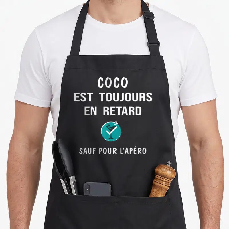 Tablier de cuisine noir avec inscription blanche Coco est toujours en retard sauf pour l'apéro et un logo de cocktail turquoise.