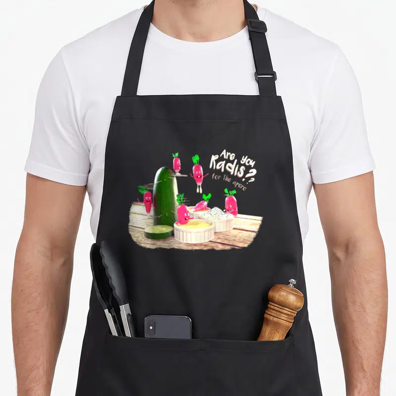 Tablier de cuisine noir avec radis anthropomorphes et texte « Are you radis for the apéro » sur fond bois.