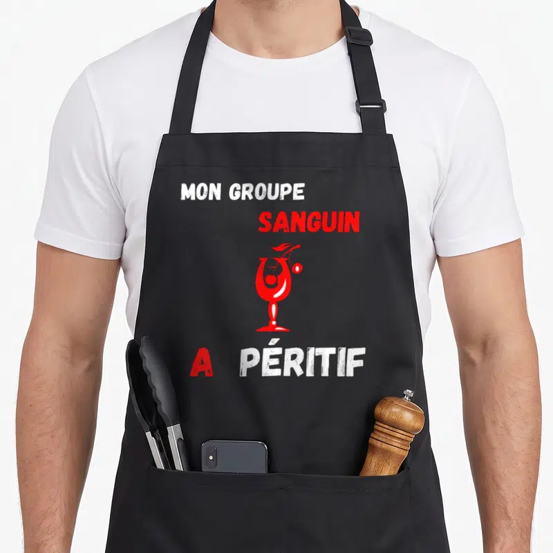 Tablier de cuisine noir avec texte Mon groupe sanguin a péritif et illustration de verre rouge stylisé au centre.