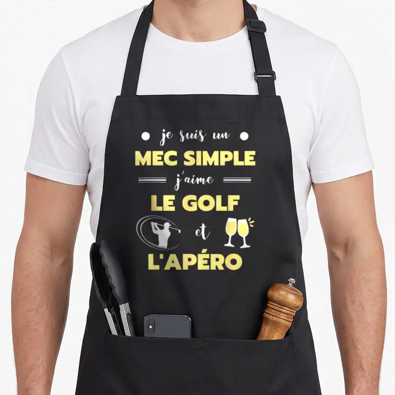 Tablier de cuisine noir avec texte jaune blanc et silhouettes golfeur et verres de champagne.