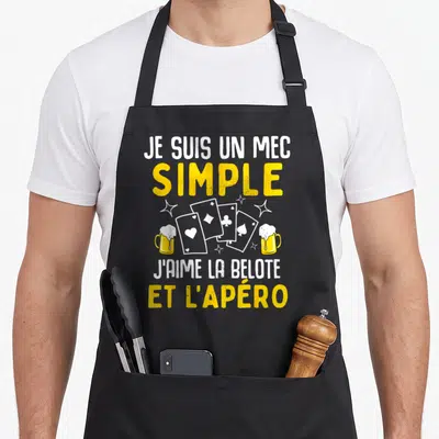 Tablier de cuisine noir avec inscription jaune et blanche sur la belote et l'apéro entourée de cartes et bières.