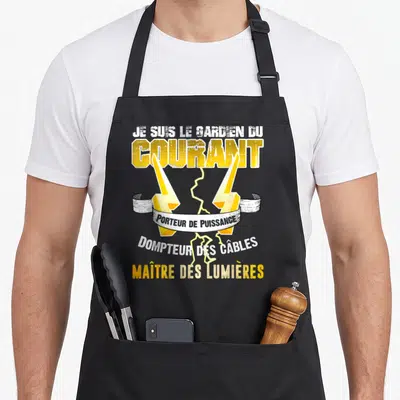 Tablier de cuisine noir avec inscription Je suis le gardien du courant et deux éclairs jaunes croisés sur fond uni.