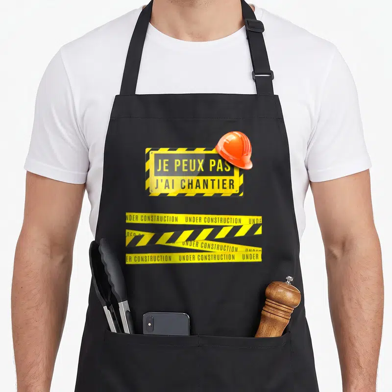 Tablier de cuisine noir avec panneau jaune Je peux pas j'ai chantier, casque orange et bandesUnder construction.