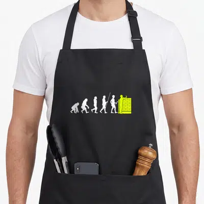 Tablier de cuisine noir avec une illustration blanche et verte montrant l'évolution d'un primates vers un maçon bâtissant un mur.
