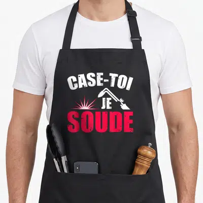 Tablier de cuisine noir avec l'inscription Case-toi Je Soude et une illustration de torche de soudage blanche et rose.