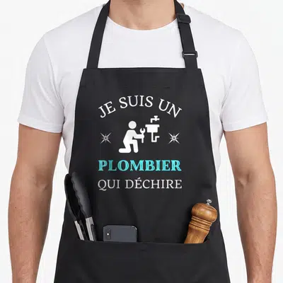 Tablier de cuisine noir avec l'inscription Je suis un plombier qui déchire et une silhouette blanche de réparateur tenant une clé à molette.