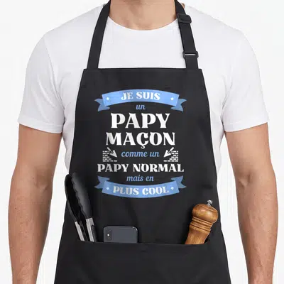 Tablier de cuisine noir avec le texte Je suis un Papy maçon comme un Papy normal mais en plus cool sur fond gris uni.