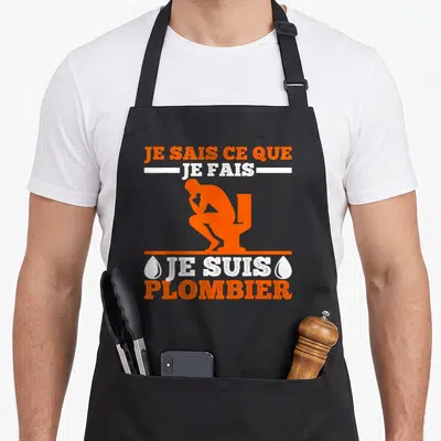 Tablier de cuisine noir avec silhouette orange d'un plombier et texte Je suis plombier en blanc et orange.