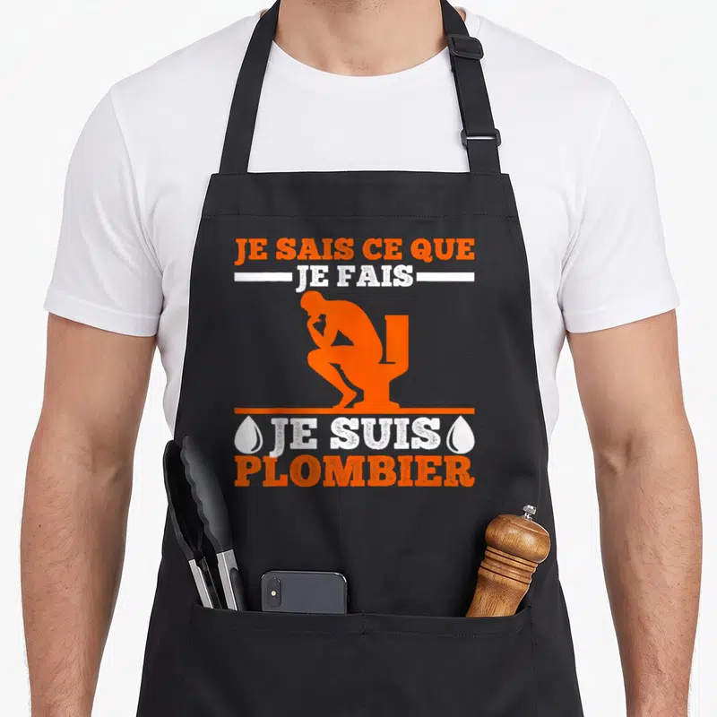 Tablier de cuisine noir avec silhouette orange d'un plombier et texte Je suis plombier en blanc et orange.