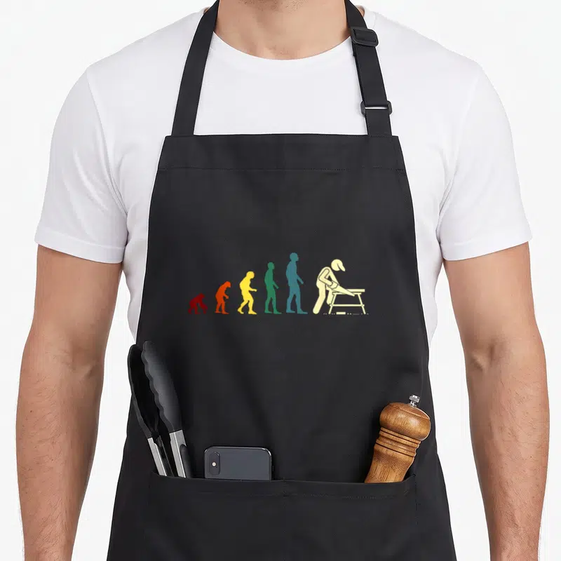 Tablier de cuisine noir avec silhouette évolutive colorée et menuisier en train de scier sur chevalet.