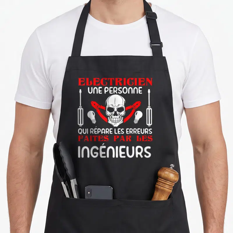 Tablier de cuisine noir avec un crâne, des pinces et le texte Électricien Ingénieurs Humor Ouvrier Lumière Homme Cadeau imprimé en rouge et blanc.