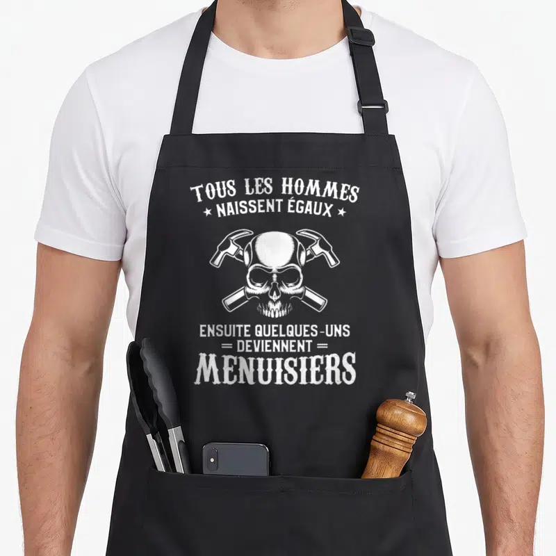Tablier de cuisine noir avec un crâne blanc surmonté de deux marteaux croisés et du texte « Tous les hommes naissent égaux ».