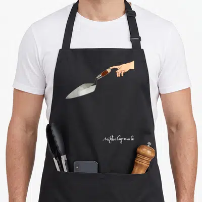 Tablier de cuisine noir avec une main tendant une truelle et la signature Ni$belagmolo en bas à droite.