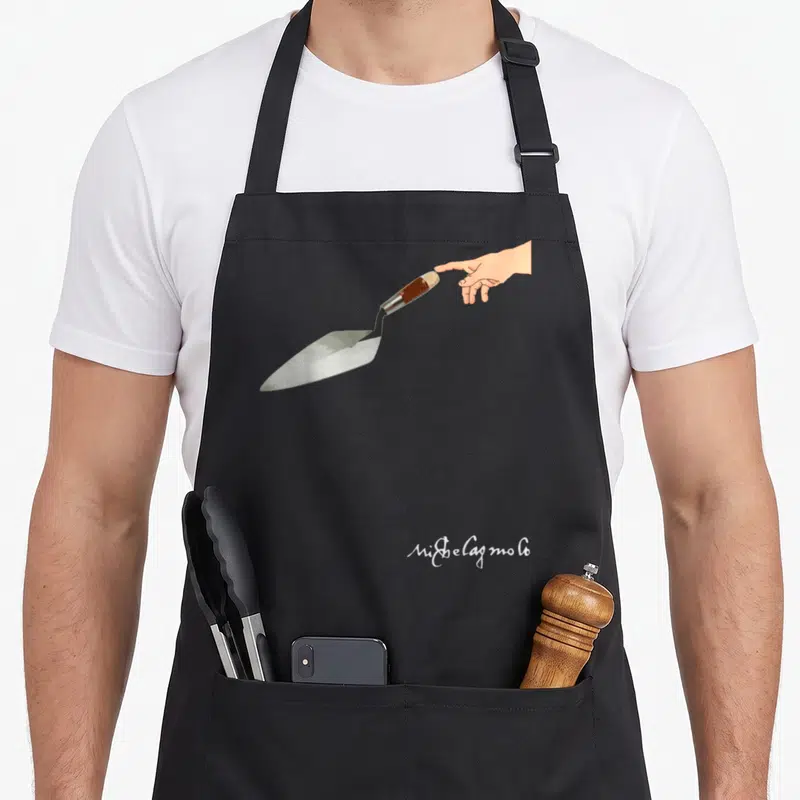Tablier de cuisine noir avec une main tendant une truelle et la signature Ni$belagmolo en bas à droite.