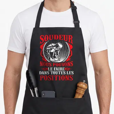 Tablier de cuisine noir avec illustration rouge et blanche d'un soudeur et texte humoristique.