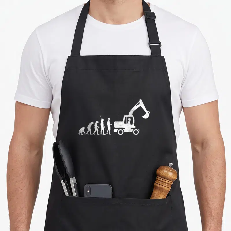 Tablier de cuisine noir avec illustration blanche de l'évolution humaine finissant par une pelle mécanique