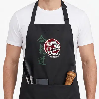 Tablier de cuisine noir avec un dragon blanc dans un cercle bordeaux et des caractères japonais verts sur le côté gauche.