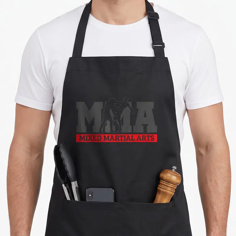 Tablier de cuisine noir avec le logo MMA et deux silhouettes d'athlètes en train de se combattre corps à corps.