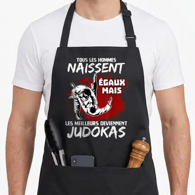 Tablier de cuisine noir avec illustration de judokas et texte blanc Tous les hommes naissent égaux mais les meilleurs deviennent judokas.