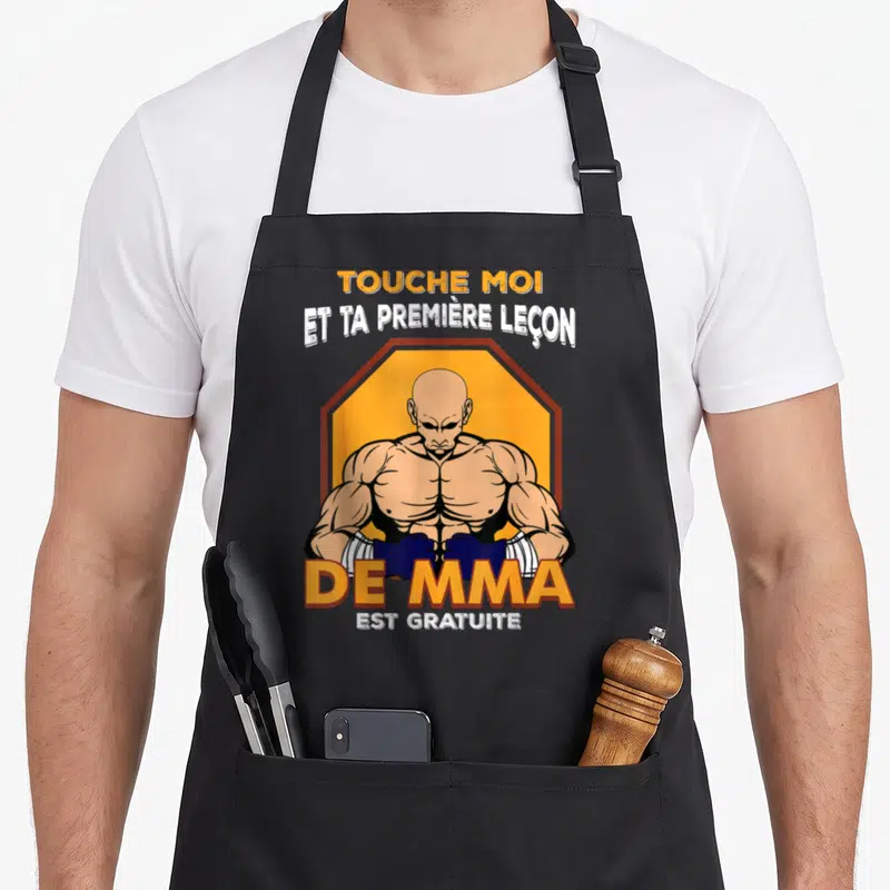 Tablier de cuisine noir avec illustration d'un combattant MMA musclé et texte humoristique sur fond orange octogonal.