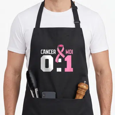 Tablier de cuisine noir avec l'inscription Cancer 0 Moi 1 et un ruban rose symbolisant la prévention du cancer du sein.