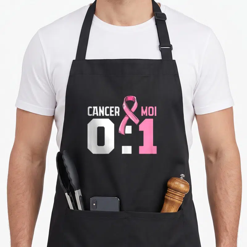 Tablier de cuisine noir avec l'inscription Cancer 0 Moi 1 et un ruban rose symbolisant la prévention du cancer du sein.