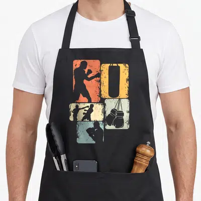 Tablier de cuisine noir avec silhouettes de boxeurs, gants et sac de frappe sur fonds orange jaune bleu et gris texturés.