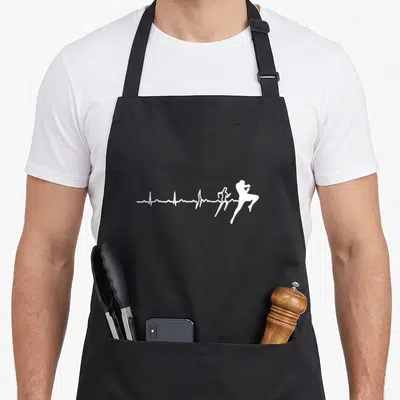 Tablier de cuisine noir avec une illustration blanche montrant une ligne de vie devenant un combattant en pleine action.