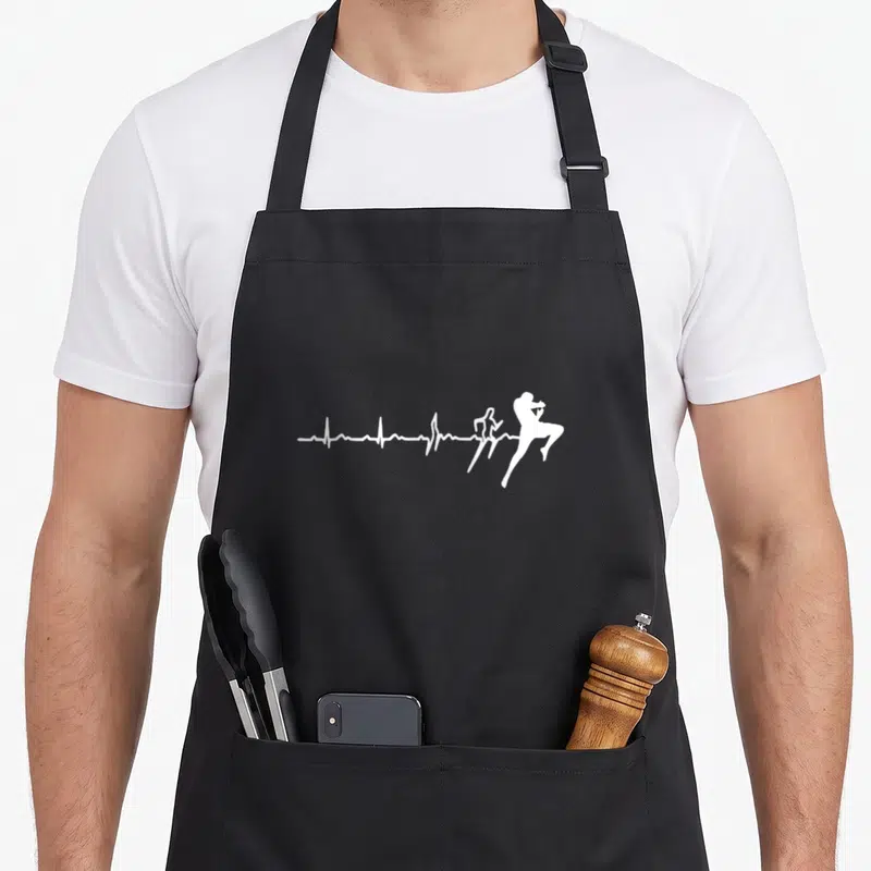 Tablier de cuisine noir avec une illustration blanche montrant une ligne de vie devenant un combattant en pleine action.