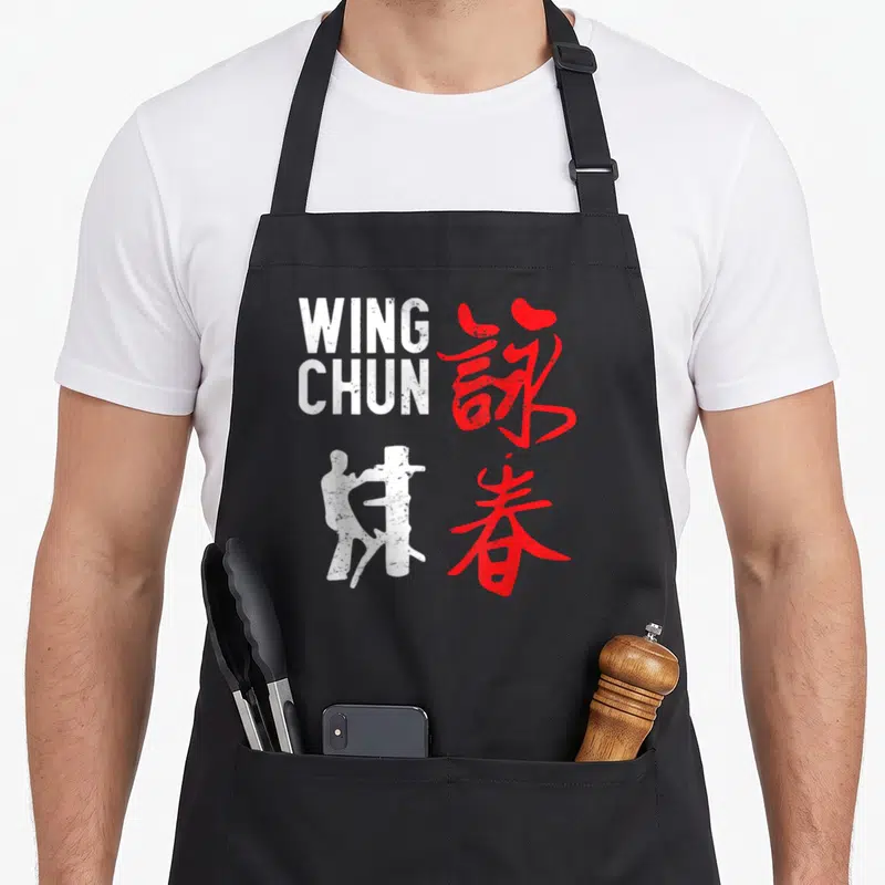Tablier de cuisine noir avec silhouette blanche, texte Wing Chun et calligraphie rouge chinoise.