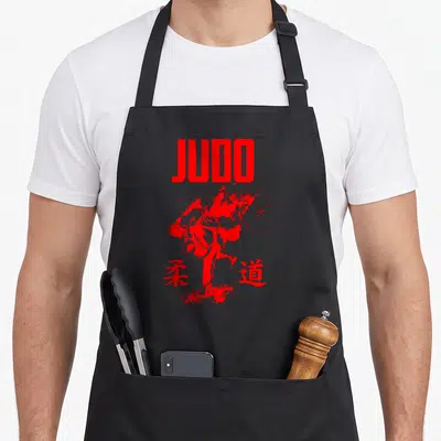 Tablier de cuisine noir avec illustration rouge d'un judoka en action et le mot JUDO en lettres capitales.