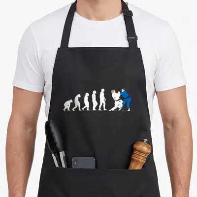 Tablier de cuisine noir avec une illustration montrant l'évolution humaine culminant par deux judokas en train de s'affronter sur le tatami.