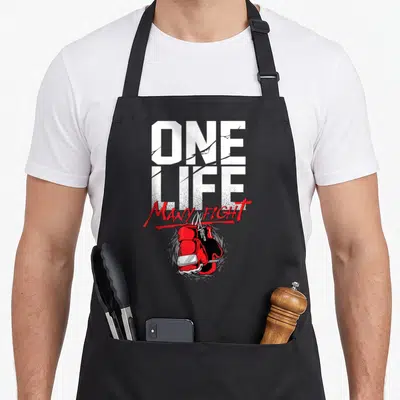Tablier de cuisine noir avec gants de boxe rouges et texte One Life Many Fight en typographie blanche et rouge.