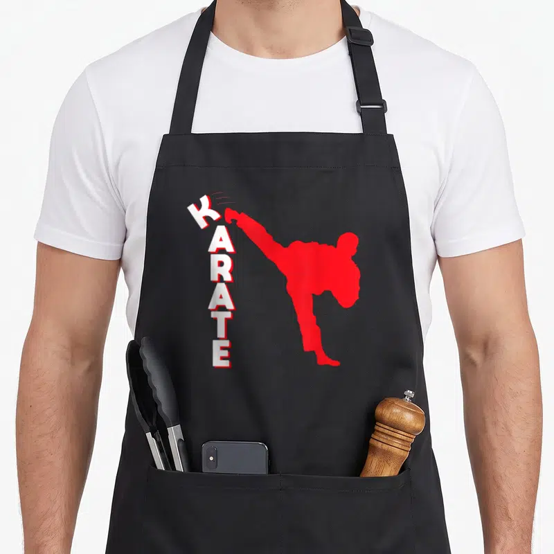 Tablier de cuisine noir avec silhouette rouge effectuant un Karaté Kick et texte vertical blanc KARATE.