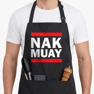 Tablier de cuisine noir avec l'inscription Nak Muay en blanc sur deux bandes rouges horizontales.
