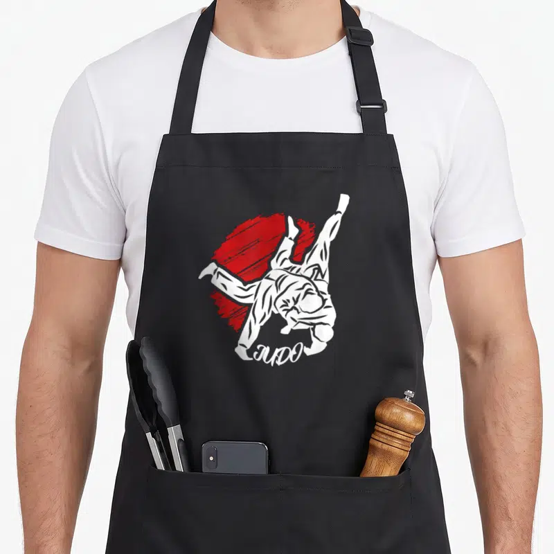 Tablier de cuisine noir avec illustration blanche d'un judoka effectuant un projection sur tache rouge et le mot JUDO.