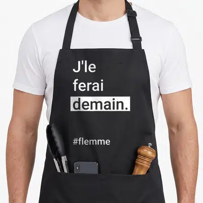 Tablier de cuisine noir avec l'inscription J'le ferai demain et le hashtag #flemme en typographie blanche minimaliste.