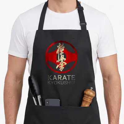 Tablier de cuisine noir avec l'emblème circulaire rouge et doré du Karate Kyokushin sur le devant.