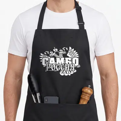 Tablier de cuisine noir avec illustration blanche représentant un aigle à deux têtes et des inscriptions en alphabet cyrillique.