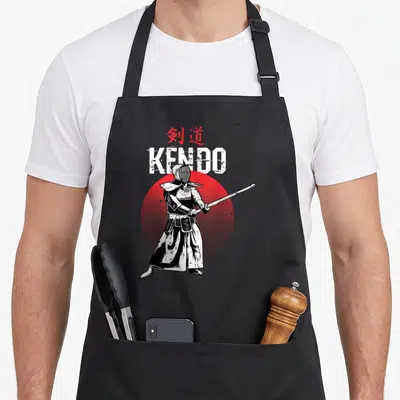 Tablier de cuisine noir avec illustration d'un kendoïka tenant un shinai devant un cercle rouge.