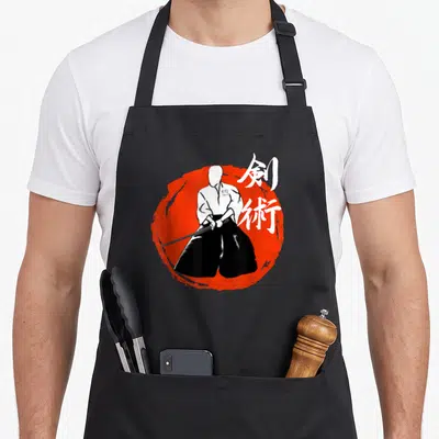 Tablier de cuisine noir avec illustration d'un guerrier Kenjutsu tenant une épée devant un cercle rouge et des kanjis blancs.