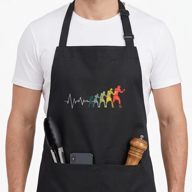 Tablier de cuisine noir avec silhouette de boxeur multicolore et ligne de battement de cœur blanche stylisée.