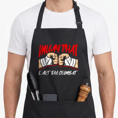 Tablier de cuisine noir avec deux poings gantés en blanc et l'inscription Muay Thai L'Art Du Combat en rouge et blanc.