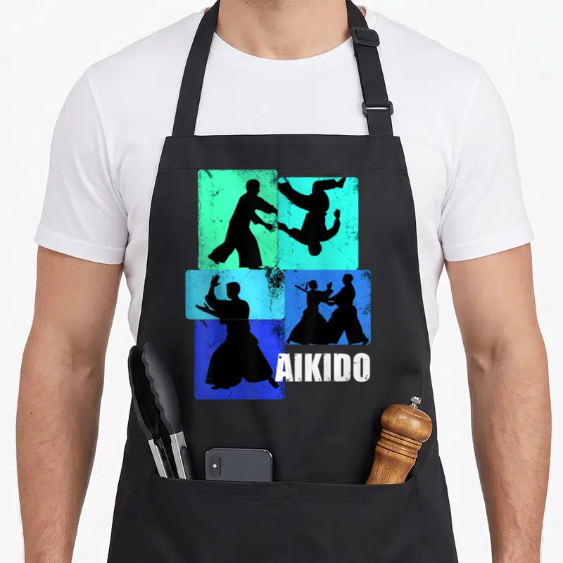 Tablier de cuisine noir avec silhouettes d'Aikidoka et le mot AIKIDO en blanc sur fonds colorés.