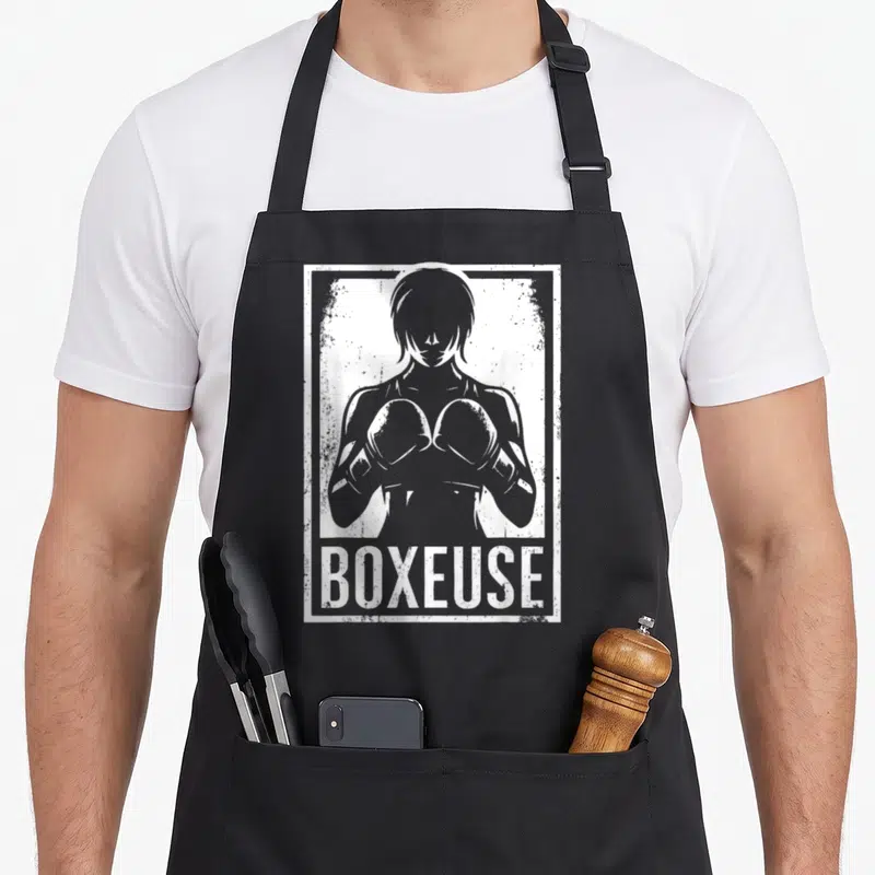 Tablier de cuisine noir avec illustration blanche d'une boxeuse et l'inscription BOXEUSE en bas.