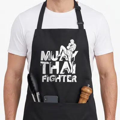 Tablier de cuisine noir avec illustration blanche d'un boxeur effectuant un coup de pied et le texte Muay Thai Fighter.